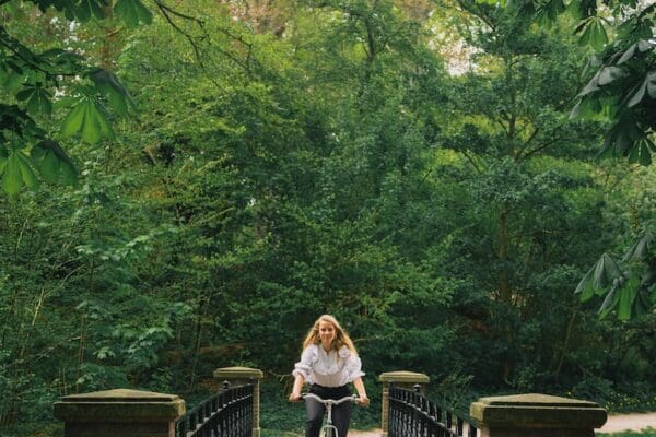a woman riding a bike across a bridge